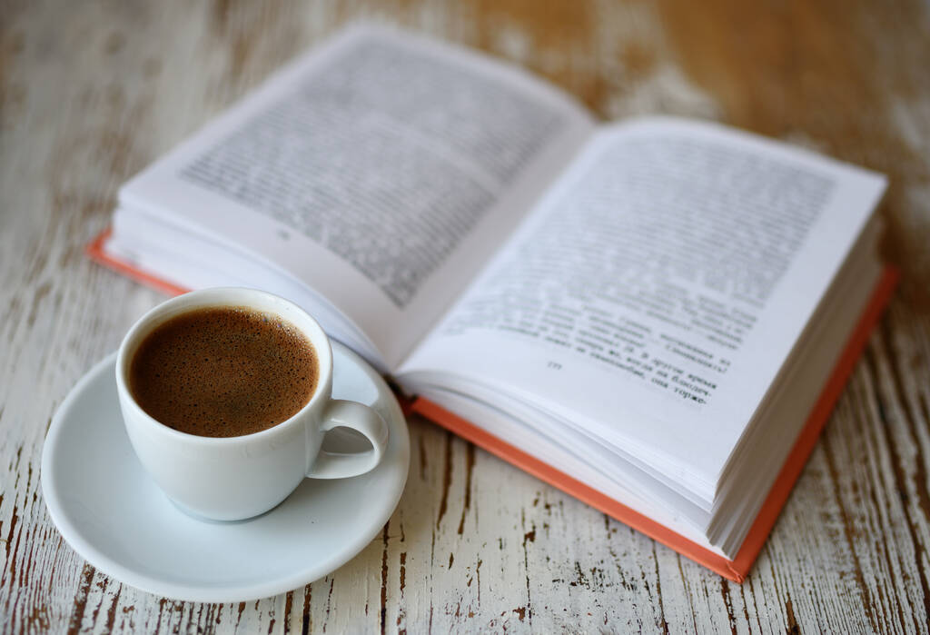 Natura morta con una tazza di caffè e un libro sul tavolo. - Foto, immagini