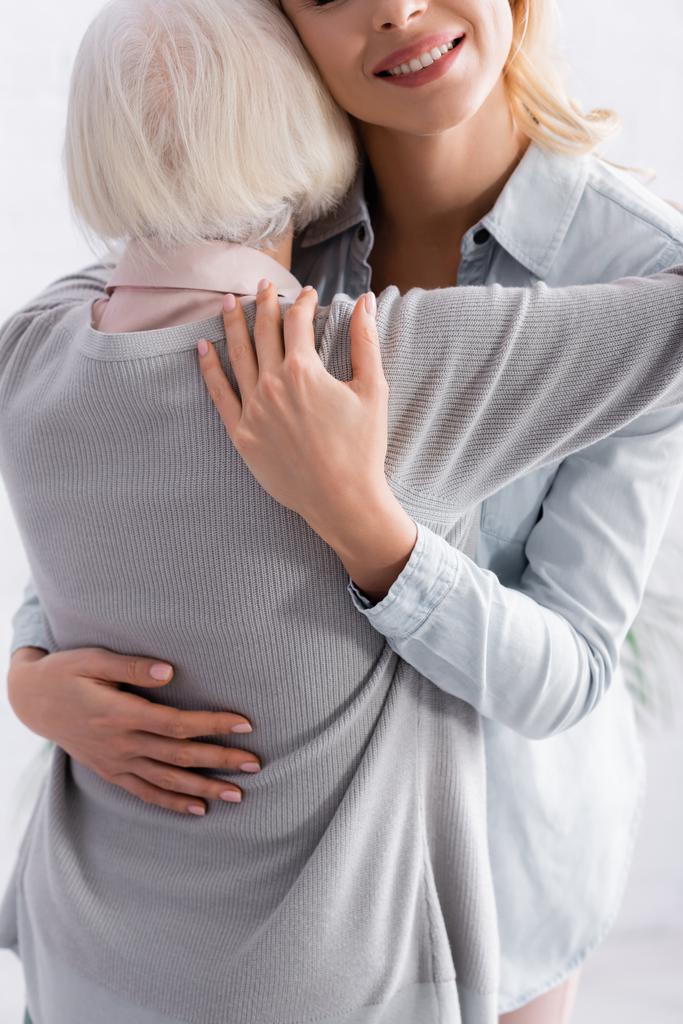 Mulher adulta cuidadosa abraçando pais de cabelos grisalhos  - Foto, Imagem