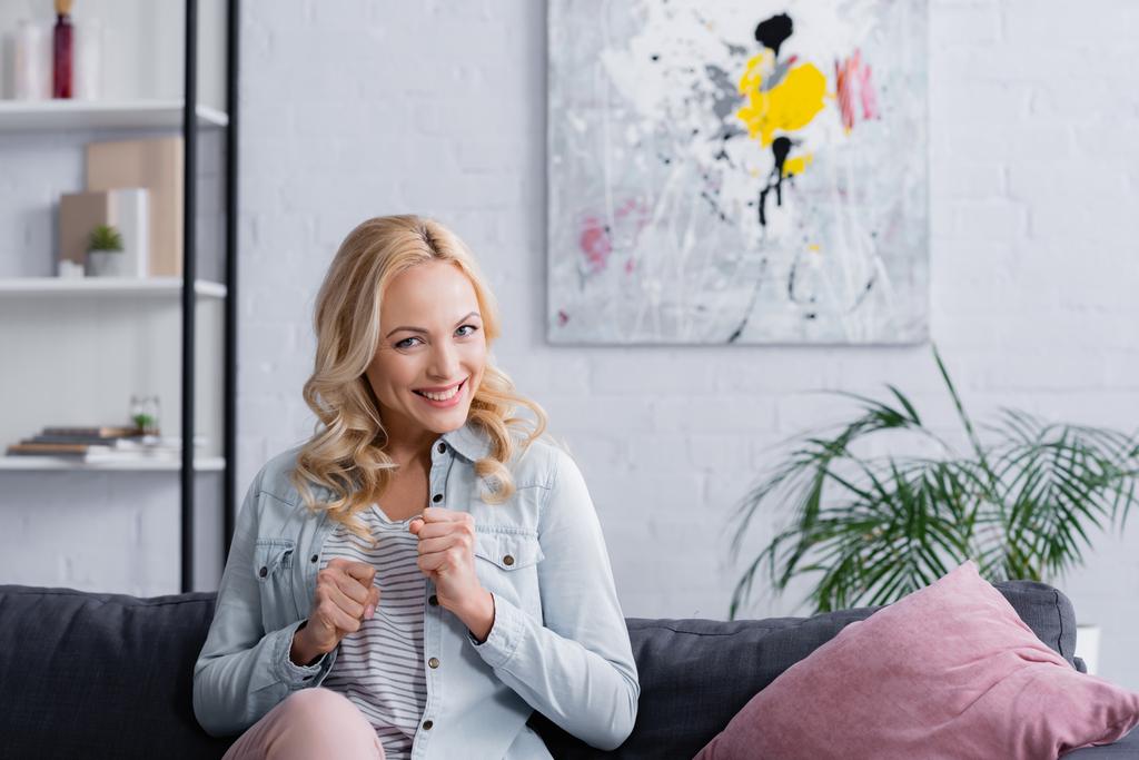 Mujer sonriente mostrando sí gesto en el sofá  - Foto, Imagen