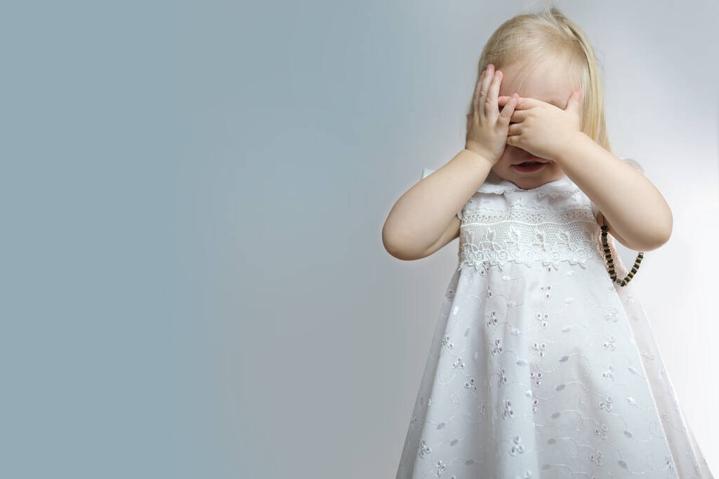 pieni lapsi, vauva, blondi tyttö seisoo, peittää kasvonsa käsillään kaunaa ja pelkoa, itku kaunaa, käsite vanhemmuuden, hyväksikäyttö, rangaistus - Valokuva, kuva
