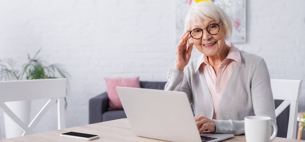 Femme âgée souriant près des gadgets et de la tasse, bannière  - Photo, image