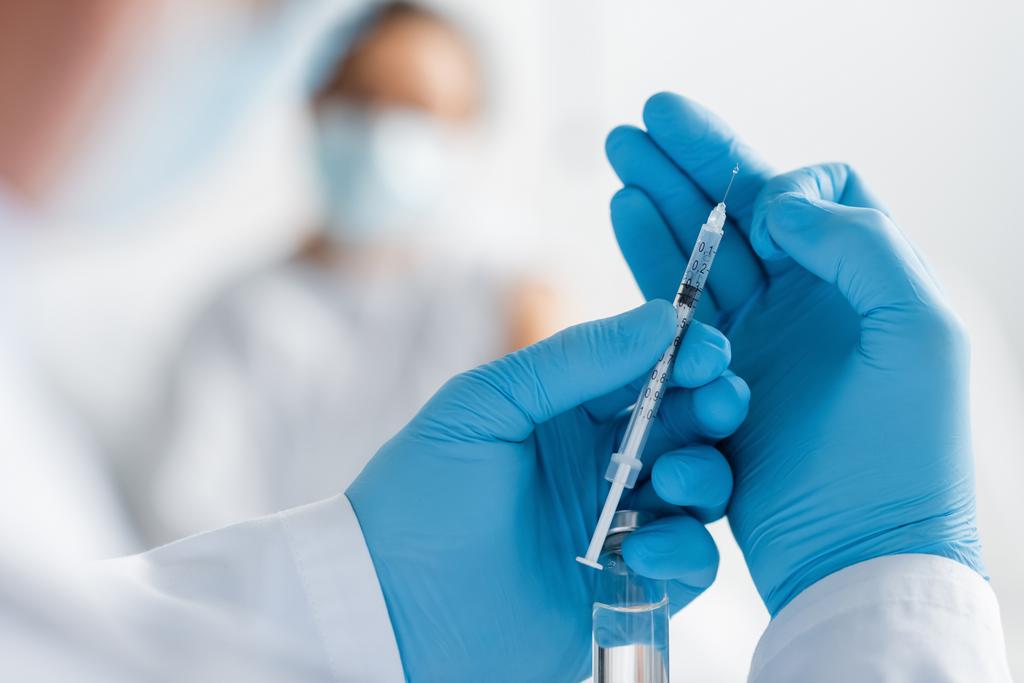 doctor in latex gloves holding syringe and vial with vaccine near african american woman on blurred background - Photo, Image