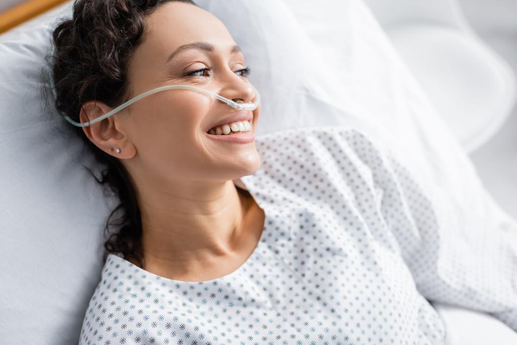Blick von oben auf freudige Afroamerikanerin mit Nasenkanüle, die im Krankenhaus wegschaut - Foto, Bild