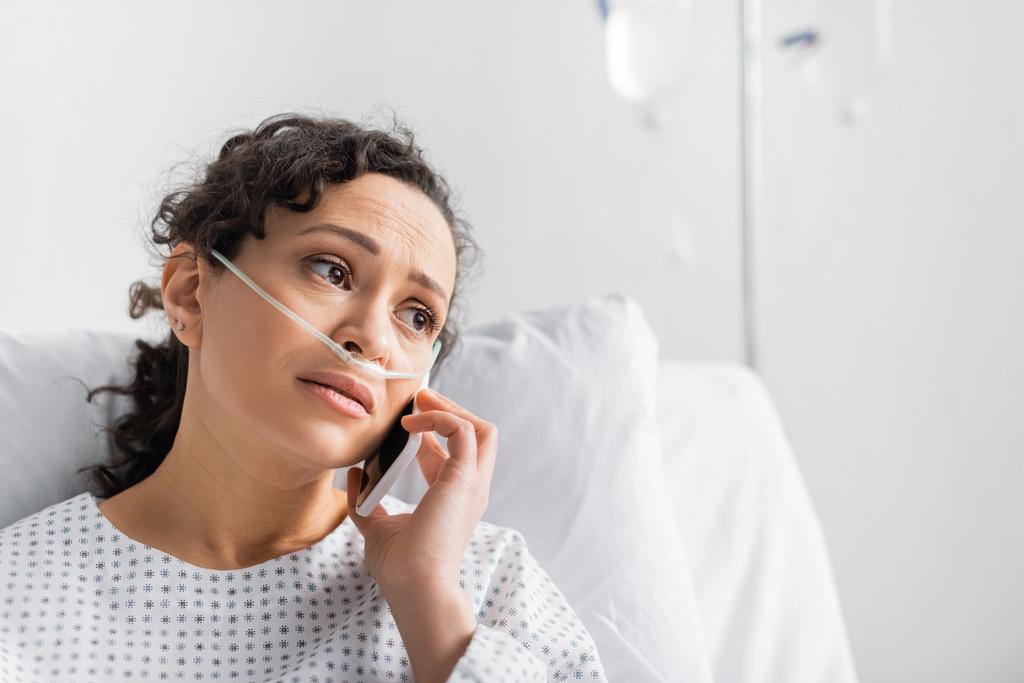 mujer afroamericana molesta mirando hacia otro lado mientras habla por teléfono móvil en la clínica - Foto, imagen