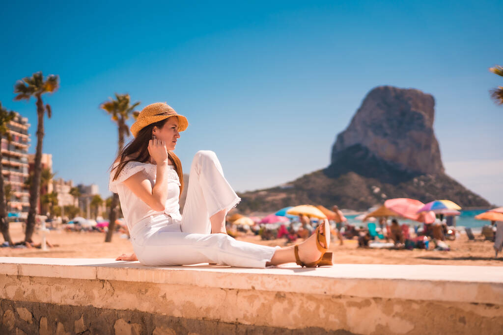 Стиль жизни молодой рыжеволосой белой девушки в белом и в соломенной шляпе на пляжах Кальпе, Валенсия. Испания - Фото, изображение