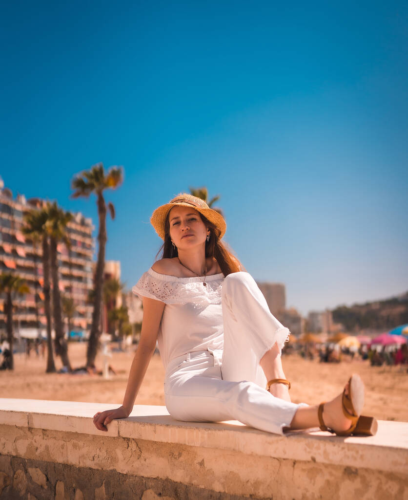 Nuoren punatukkaisen valkoisiin pukeutuneen valkoihoisen tytön elämäntapa ja olkihattu Calpen rannalla Valenciassa. Espanjasta. Välimerestä nauttiminen - Valokuva, kuva