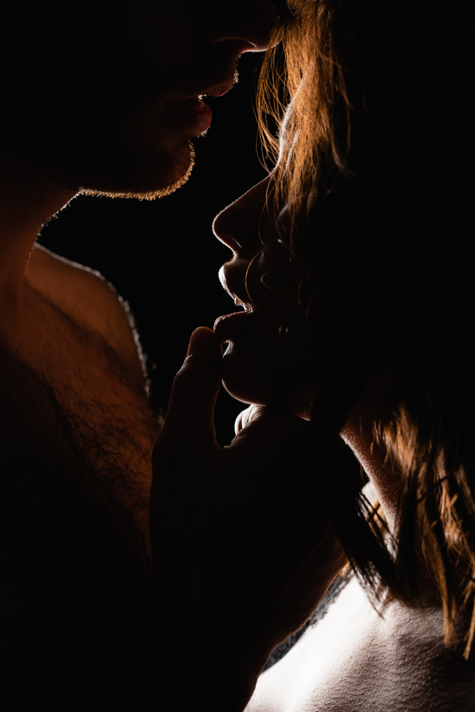 osvětlení na muže dotýkání rty sexy ženy izolované na černé - Fotografie, Obrázek