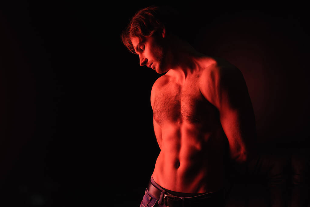 červené osvětlení na těle sexy svalnatý muž stojící izolované na černé  - Fotografie, Obrázek