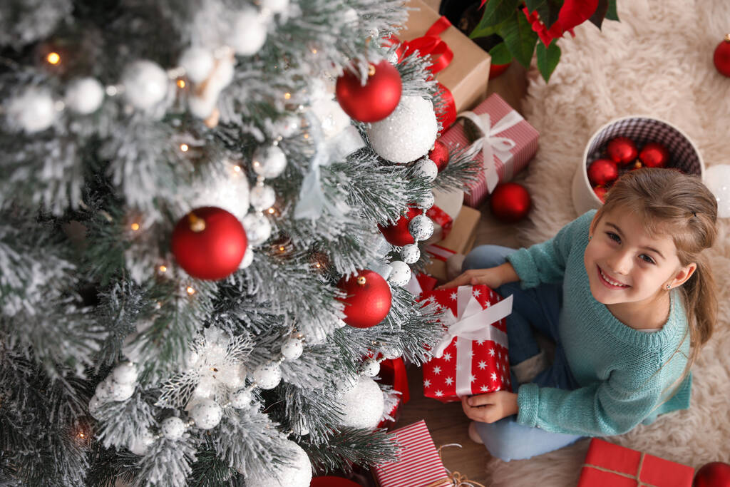 Милая маленькая девочка с рождественским подарком дома, над видом - Фото, изображение
