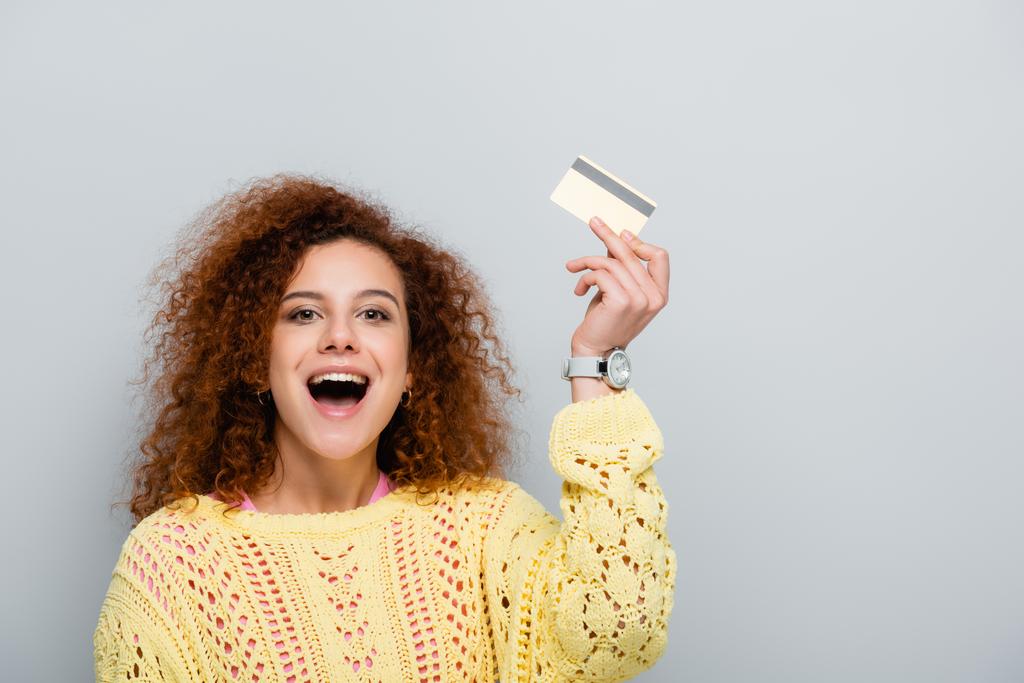 mulher animado com boca aberta segurando cartão de crédito isolado no cinza - Foto, Imagem