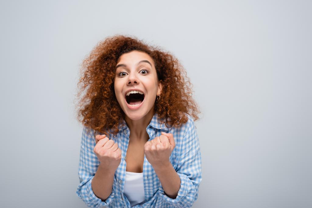 podekscytowana kobieta wykazująca się zwycięskim gestem i krzykiem odizolowana na szaro - Zdjęcie, obraz