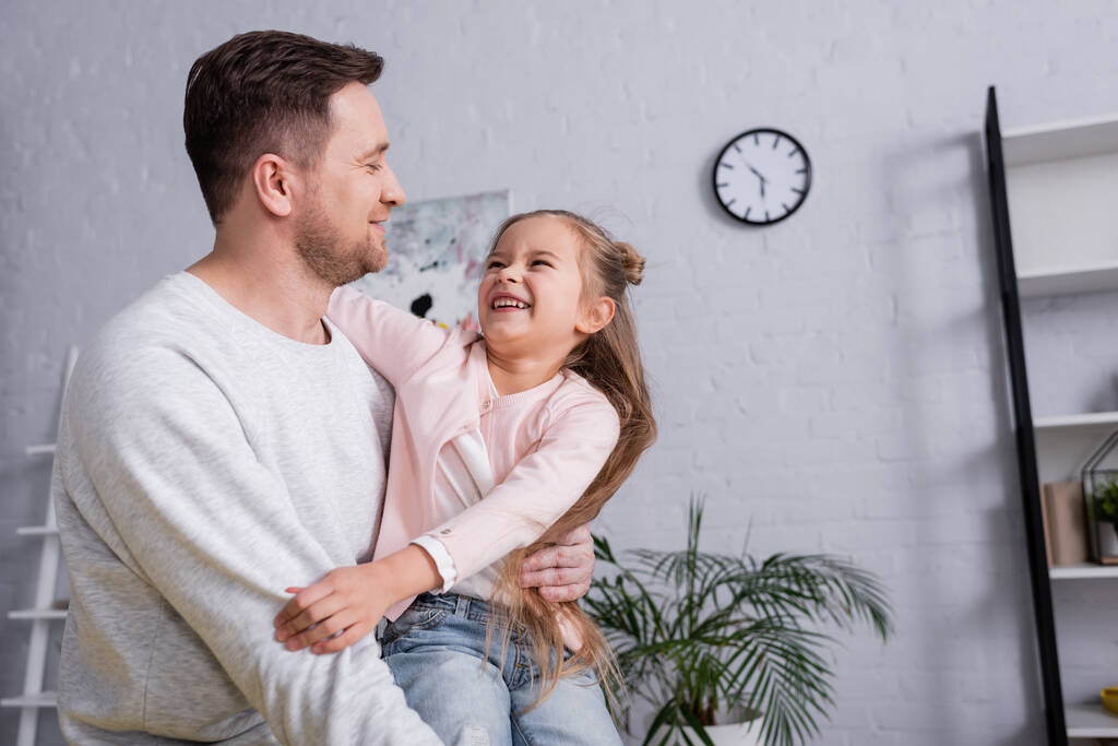 Sorridente uomo abbracciando figlia in soggiorno  - Foto, immagini