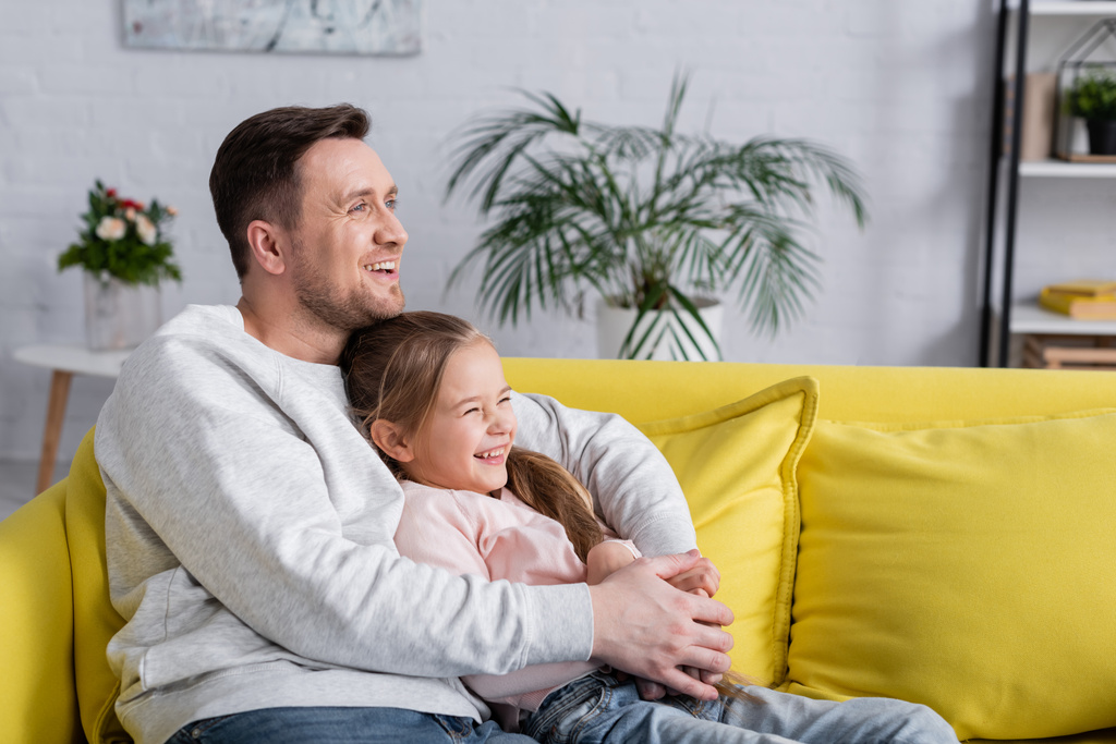 Onnellinen lapsi istuu lähellä isää olohuoneessa  - Valokuva, kuva