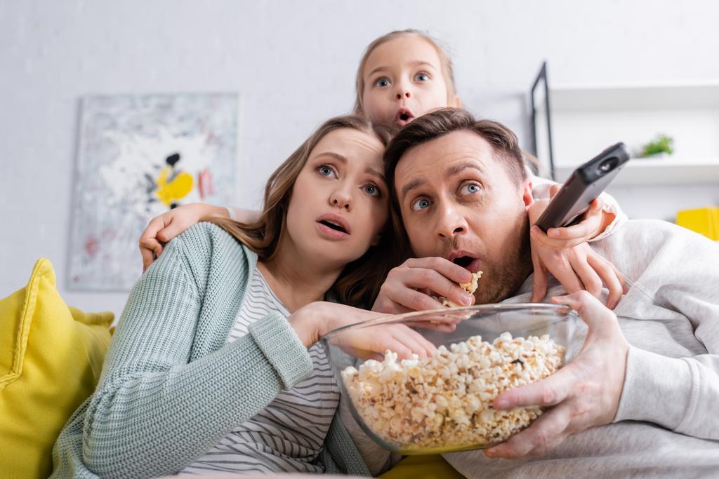Испуганная семья с попкорном смотрит фильм на диване  - Фото, изображение
