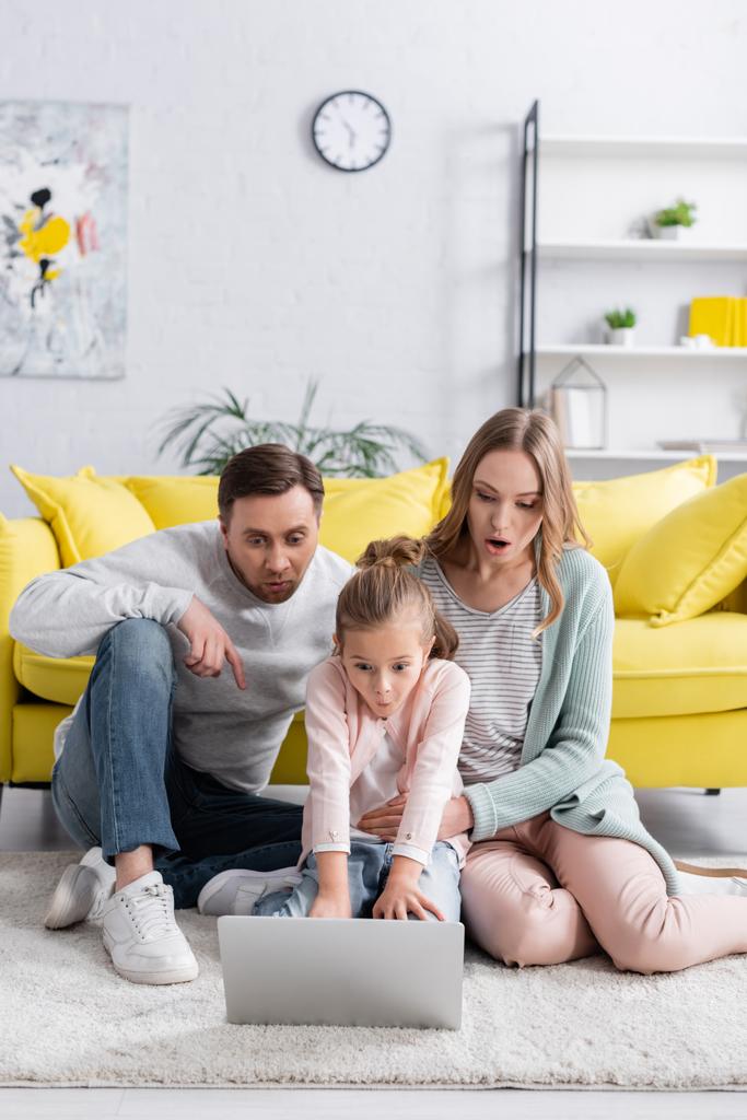 Verbazingwekkende familie met laptop op de vloer in de woonkamer  - Foto, afbeelding