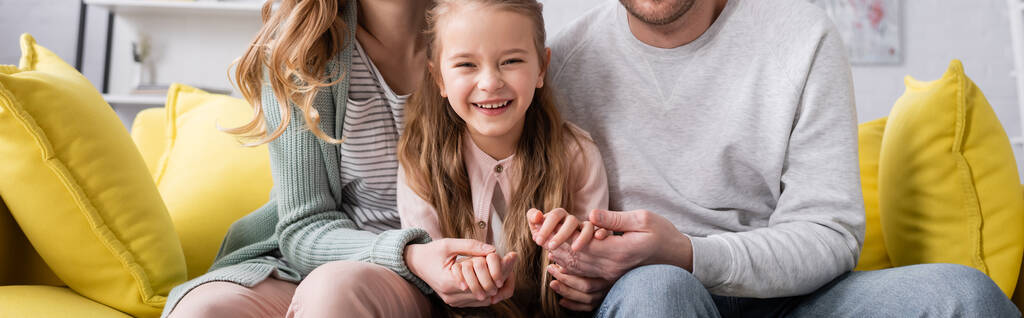 Hymyilevä lapsi pitää kädestä vanhempien sohvalla, banneri  - Valokuva, kuva