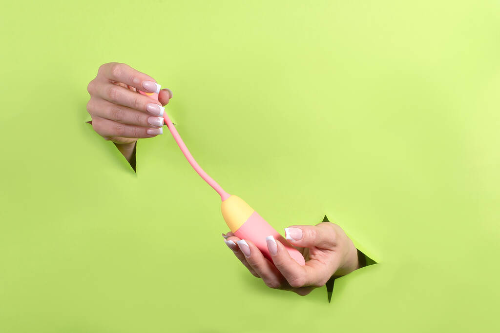 Еротична іграшка для дорослих тільки в жіночих руках на зеленому тлі, жіноче задоволення і задоволення
. - Фото, зображення