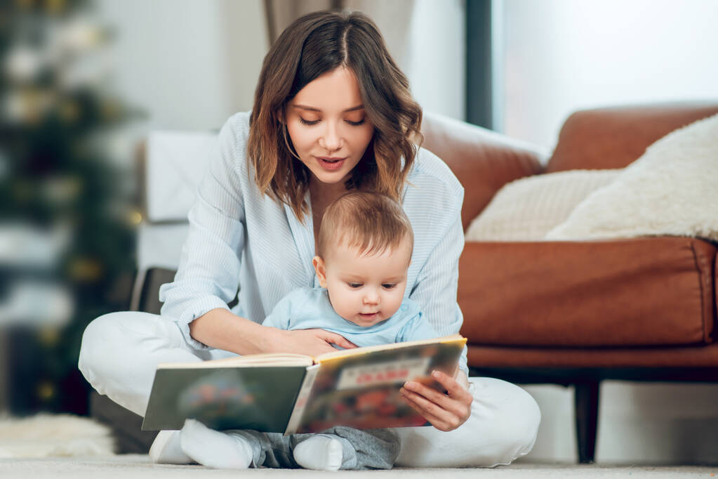 Focused mom reading book to small child - Foto, imagen