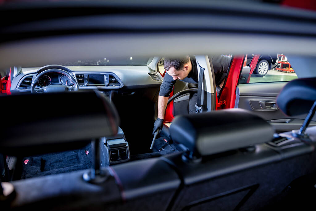 Car service worker cleaning car interior with a vacuum cleaner - Photo, Image