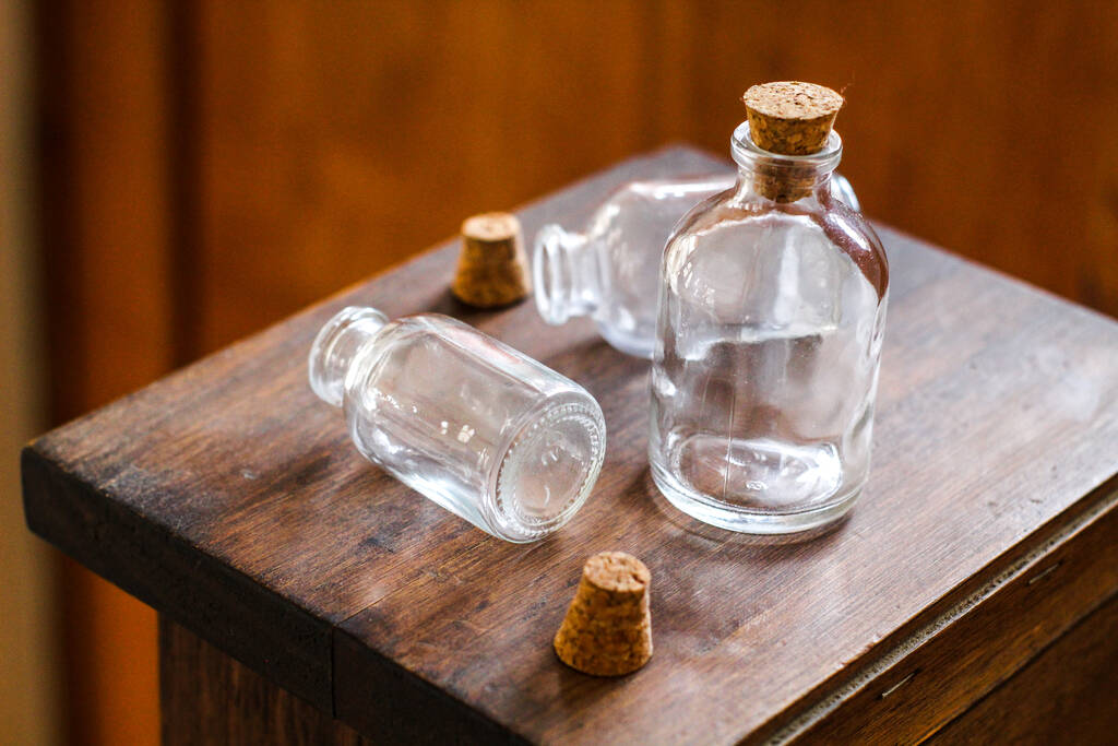 Κοντινό πλάνο των τριών γυάλινων μπουκαλιών με φελλούς στο ξύλινο τραπέζι - Φωτογραφία, εικόνα