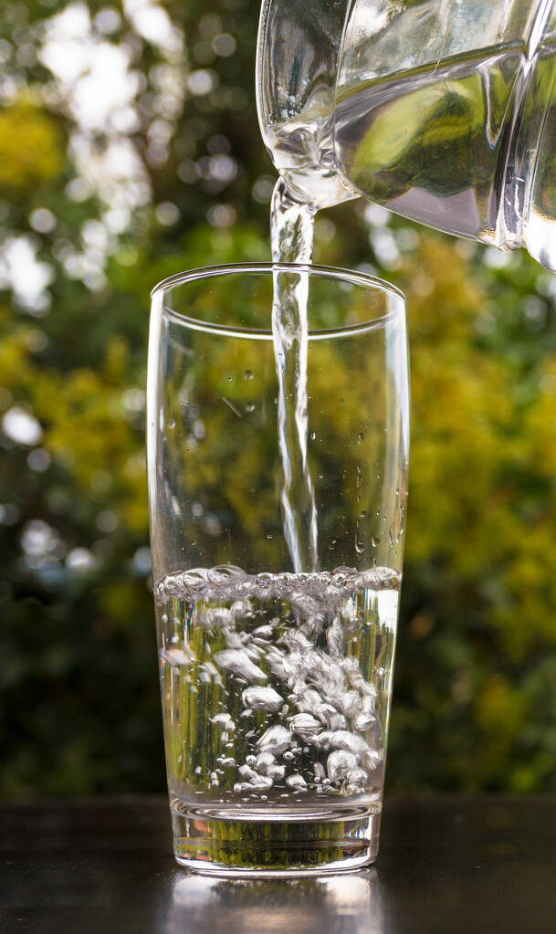 Un primer plano de agua vertiendo en un vaso - Foto, imagen