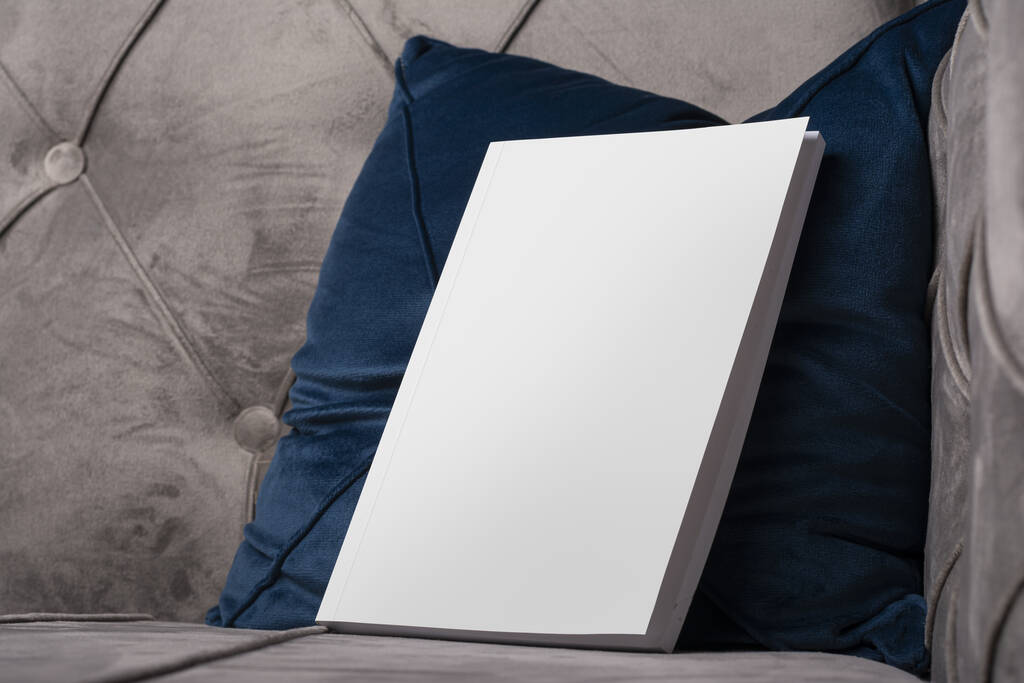 Eine Nahaufnahme eines Buches mit leerem Einband mit Platz für Text auf einem Kissen auf dem Sofa - Foto, Bild