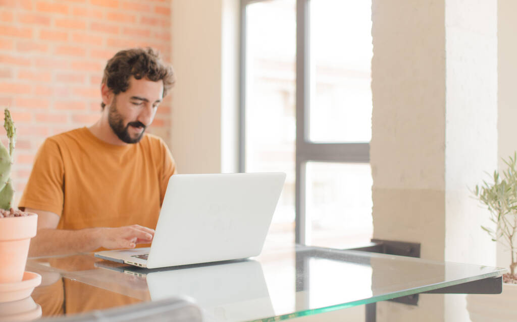 jonge man met baard werken thuis met een laptop - Foto, afbeelding