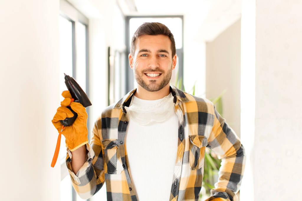 handyman smiling happily with a hand on hip and confident, positive, proud and friendly attitude - Photo, Image