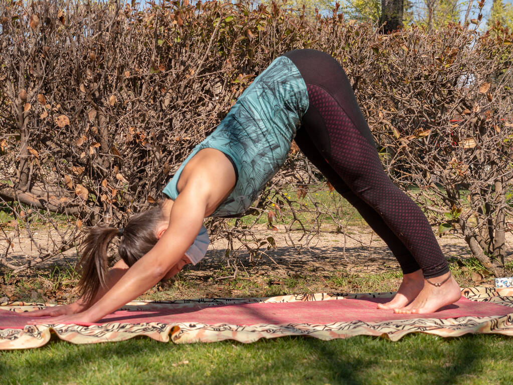 Een Spaanse brunette vrouw oefenen yoga in een park op een zonnige dag - Foto, afbeelding
