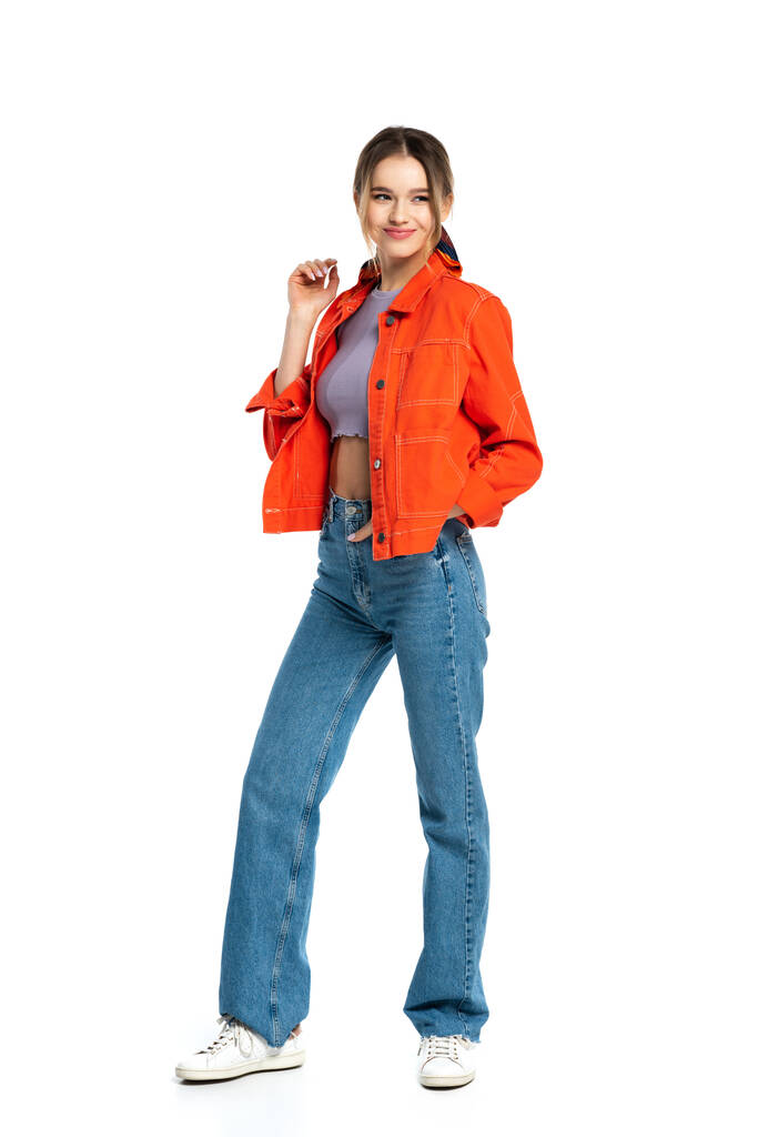 piena lunghezza di piacere giovane donna in crop top e camicia arancione in piedi isolato su bianco  - Foto, immagini