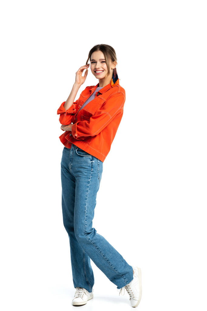 volle Länge der fröhlichen jungen Frau in orangefarbenem Hemd, die isoliert auf weiß steht  - Foto, Bild