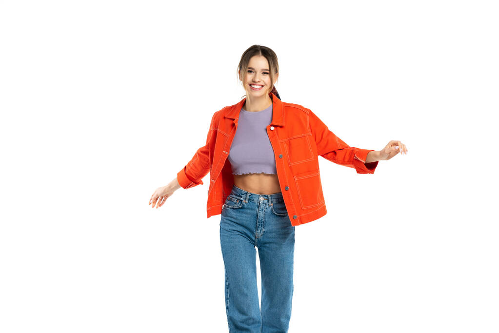 vrolijk jong vrouw in jeans, gewas top en oranje shirt poseren geïsoleerd op wit - Foto, afbeelding