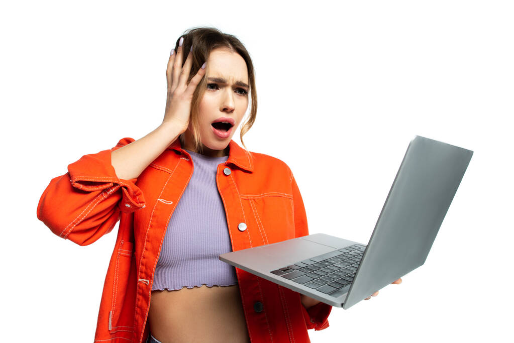 Şok olmuş turuncu tişörtlü kadın beyaz dizüstü bilgisayara bakıyor.  - Fotoğraf, Görsel