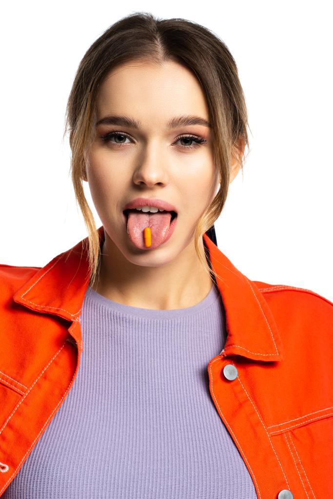 joven mujer sobresaliendo lengua con cápsula aislada en blanco  - Foto, imagen