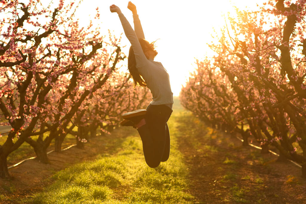 Profil podekscytowanej kobiety skaczącej szczęśliwie na polu o wschodzie słońca - Zdjęcie, obraz