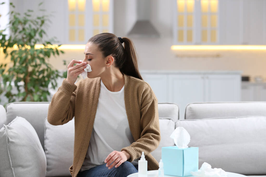 Mujer enferma con papel estornudando en casa - Foto, Imagen