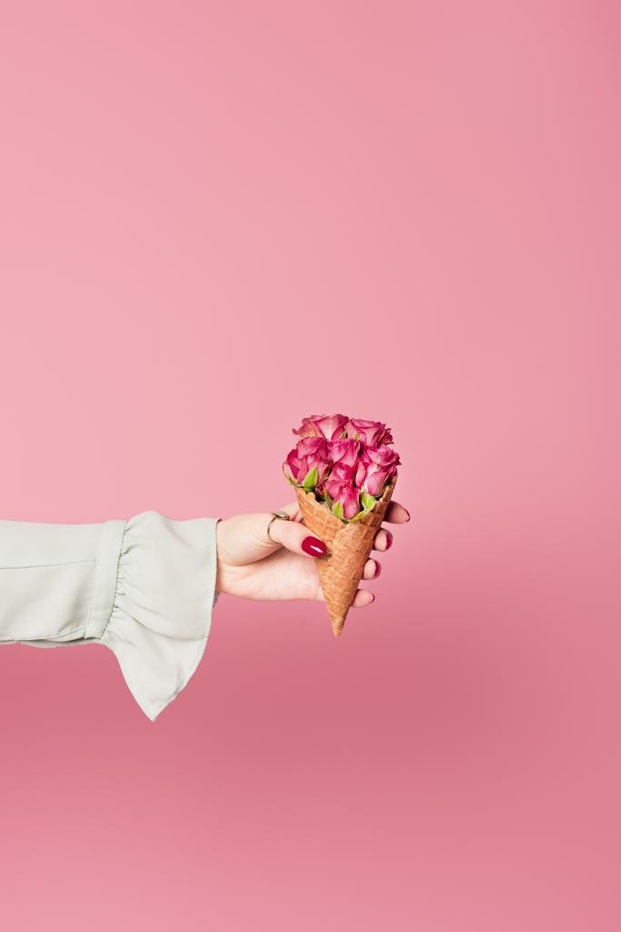 Gewassen beeld van de vrouw met rode manicure houden wafel kegel en bloemen geïsoleerd op roze  - Foto, afbeelding