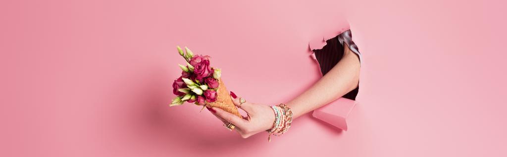 Częściowy widok kobiety trzymającej róg wafla w otworze w różowym tle, baner  - Zdjęcie, obraz