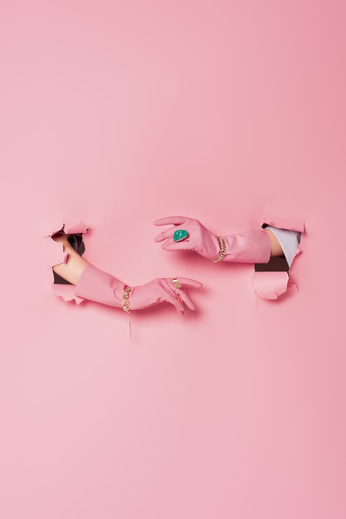 Przycięty widok kobiety w rękawiczkach i akcesoriach w pobliżu różowego tła z otworami  - Zdjęcie, obraz