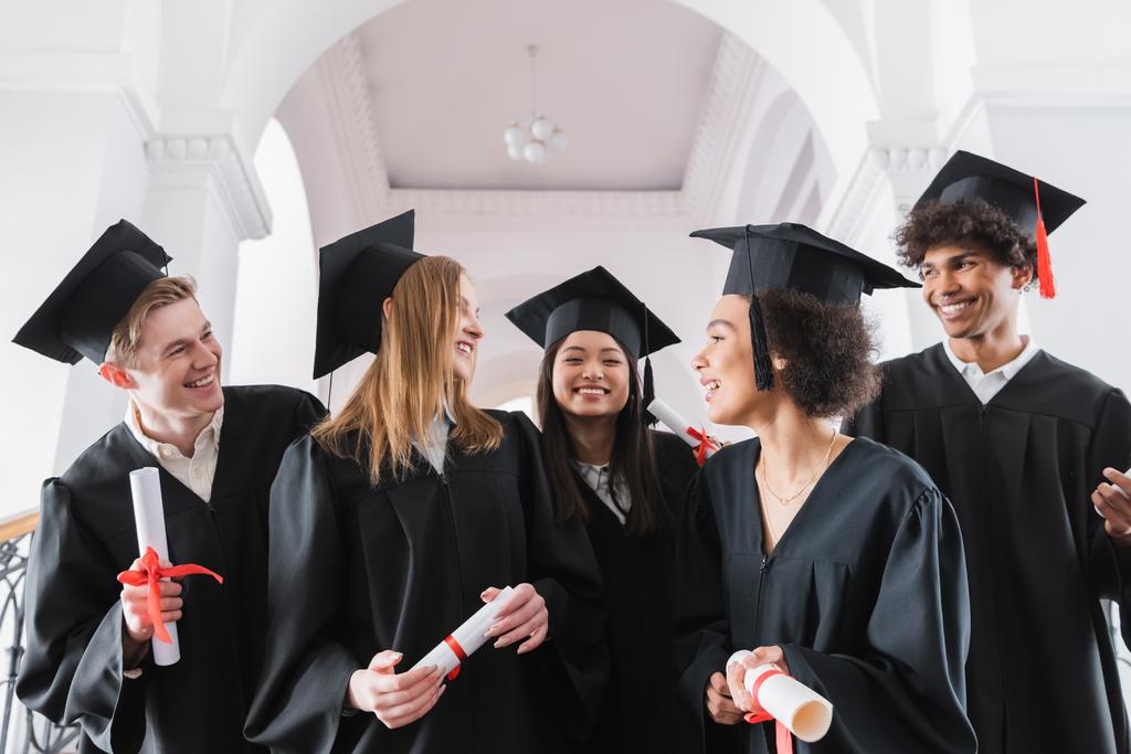 Sorrindo interracial graduados olhando uns para os outros na universidade  - Foto, Imagem
