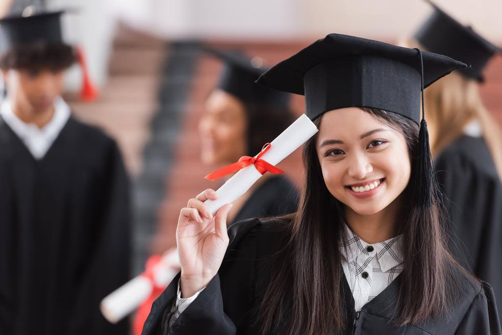 Asiatique diplômé en chapeau souriant et titulaire d'un diplôme  - Photo, image