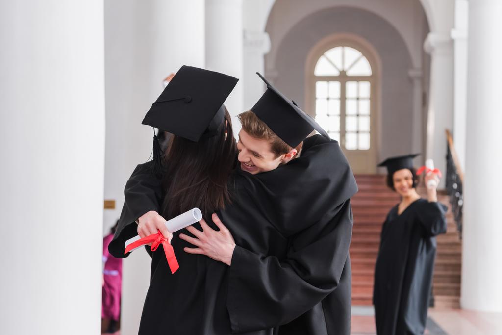 Laureato sorridente con diploma abbracciare amico  - Foto, immagini
