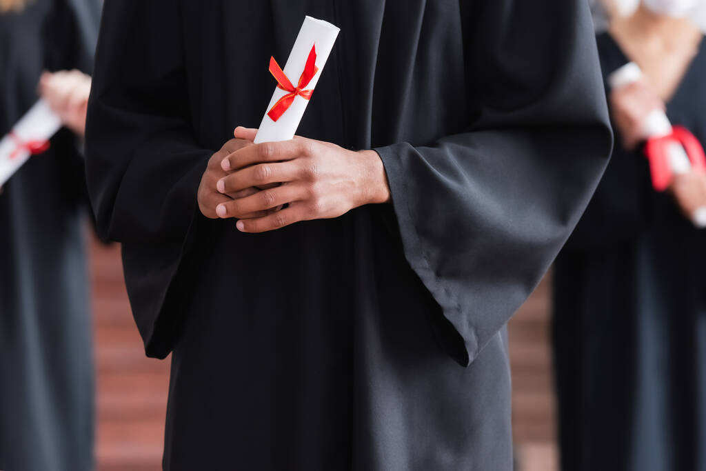 Розбитий погляд на диплом в руках афроамериканського випускника  - Фото, зображення