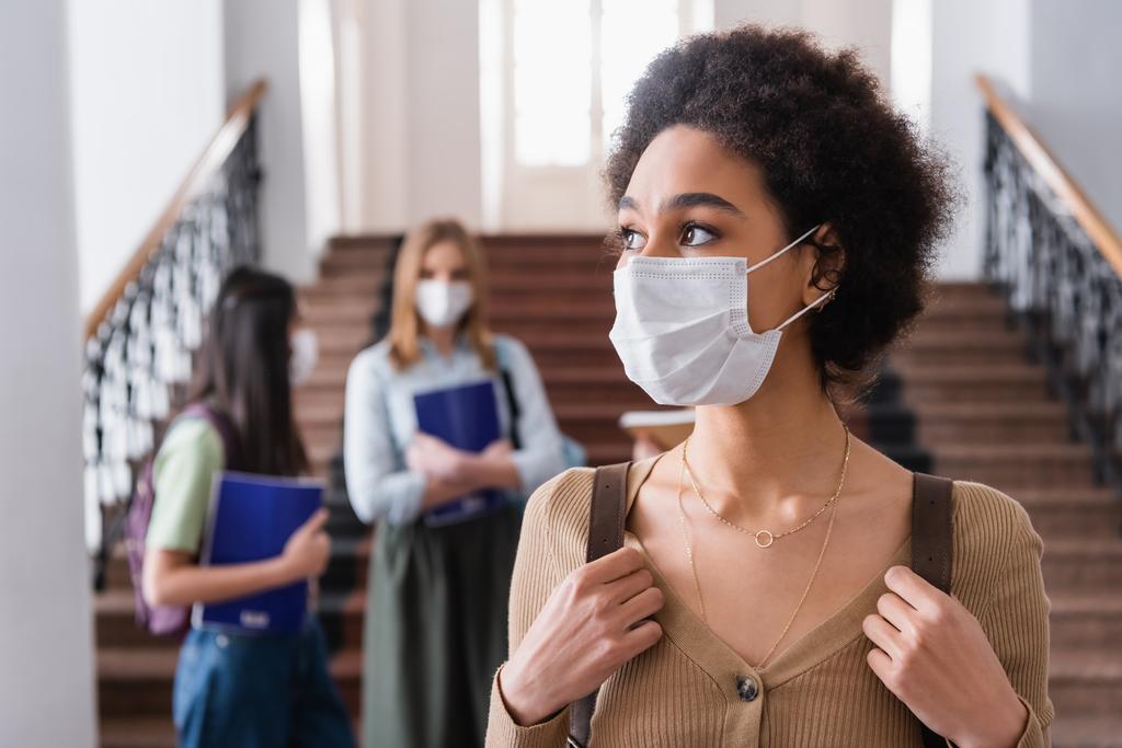 Étudiant afro-américain dans un masque médical tenant un sac à dos - Photo, image