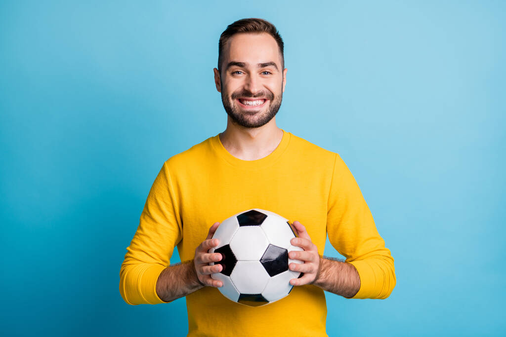 Foto de joven guapo feliz positivo sonriente alegre hombre mantenga pelota de fútbol aislado sobre fondo de color azul - Foto, Imagen