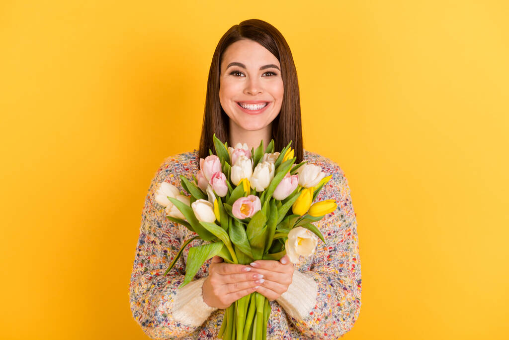 Fotografie okouzlující krásná mladá žena držet jaro květiny úsměv dovolená izolované na žlutém pozadí - Fotografie, Obrázek