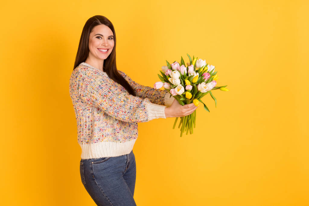 Profile side photo of attractive cheerful young lady give flowers tulips empty space isolated on yellow color background - Photo, Image