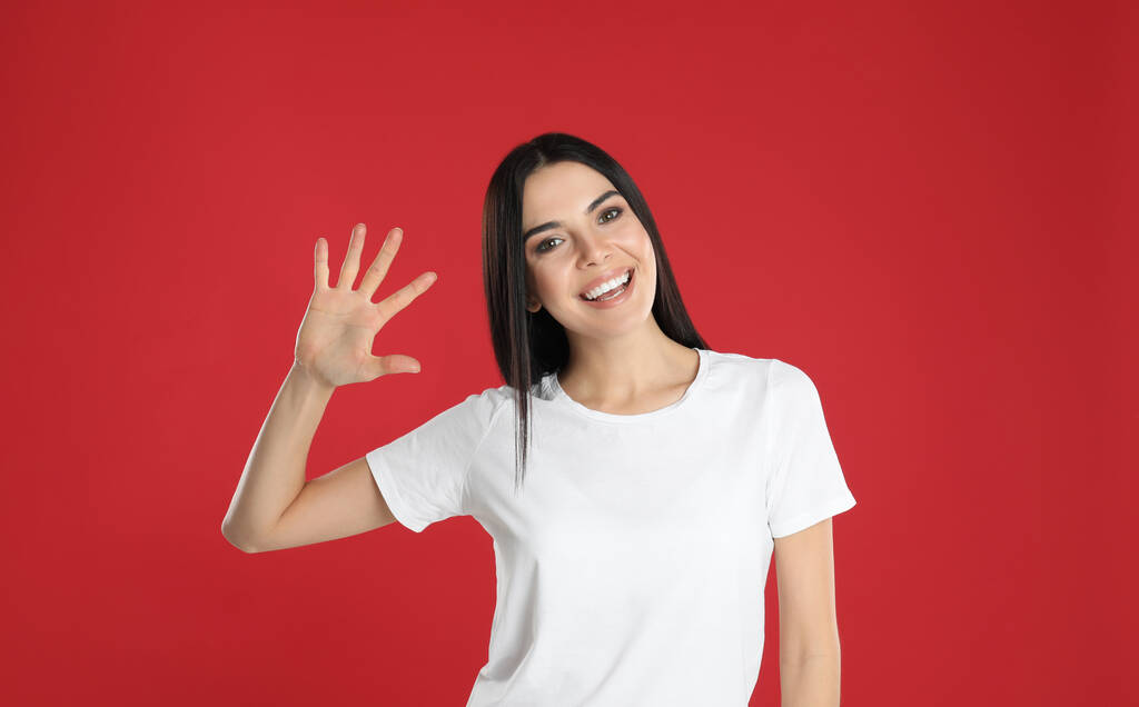 Nő mutatja az ötös számú kezét a piros háttér - Fotó, kép