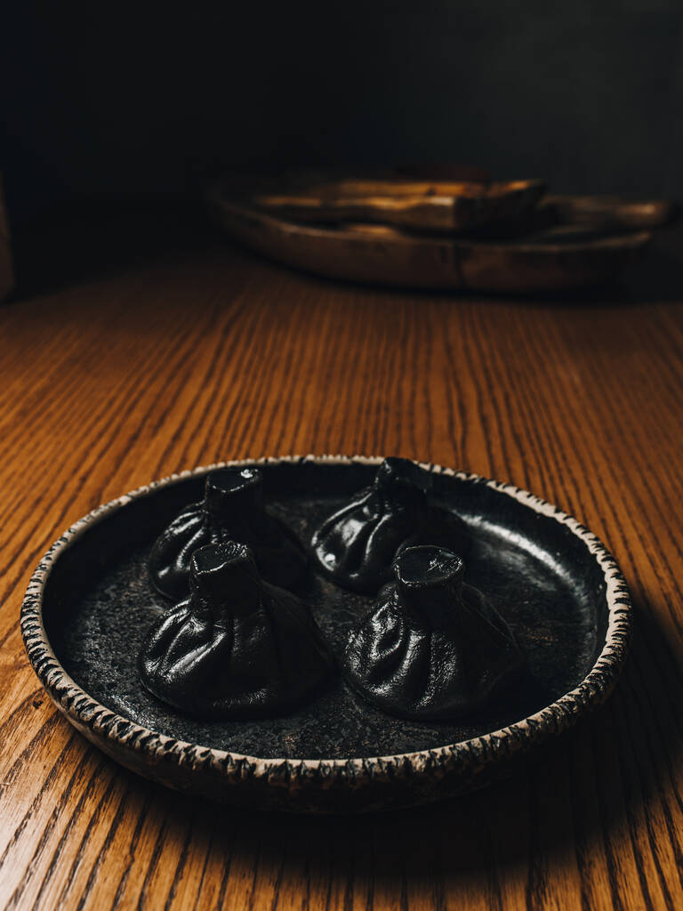 Khinkali negro en la placa negra. Comida georgiana - Foto, imagen