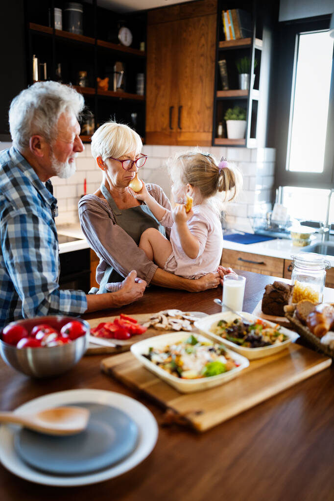 Glückliches Enkelmädchen beim Frühstück mit den Großeltern zu Hause - Foto, Bild